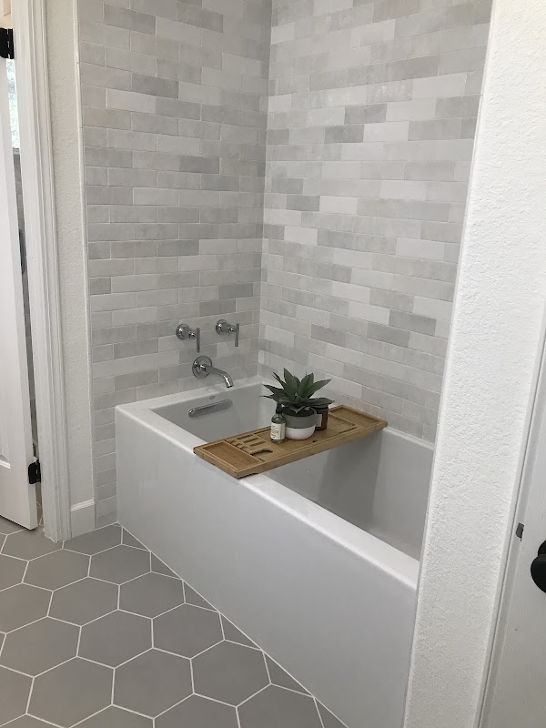 Bathroom tub alcove with soft white subway tile and hexagon floor tile